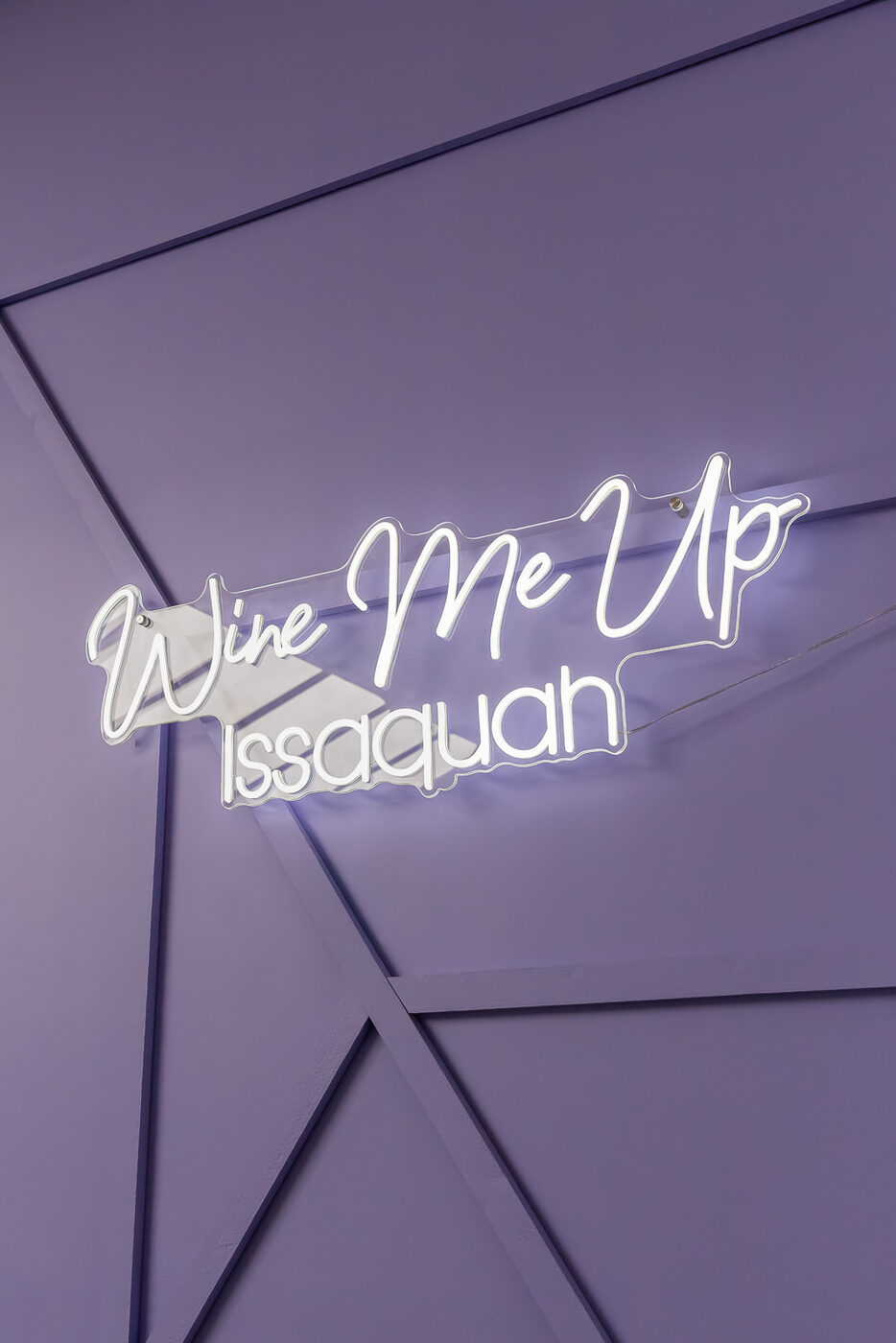 Two glasses of rosé clinking in front of a pink neon sign